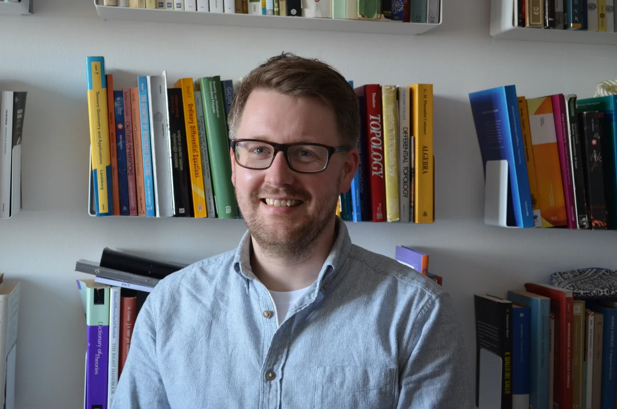 Portrait of Paul Breiding in front of a bookshelf