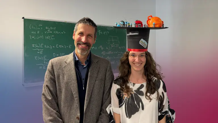 László Székelyhidi and Sandra Ried smile in front of a blackboard