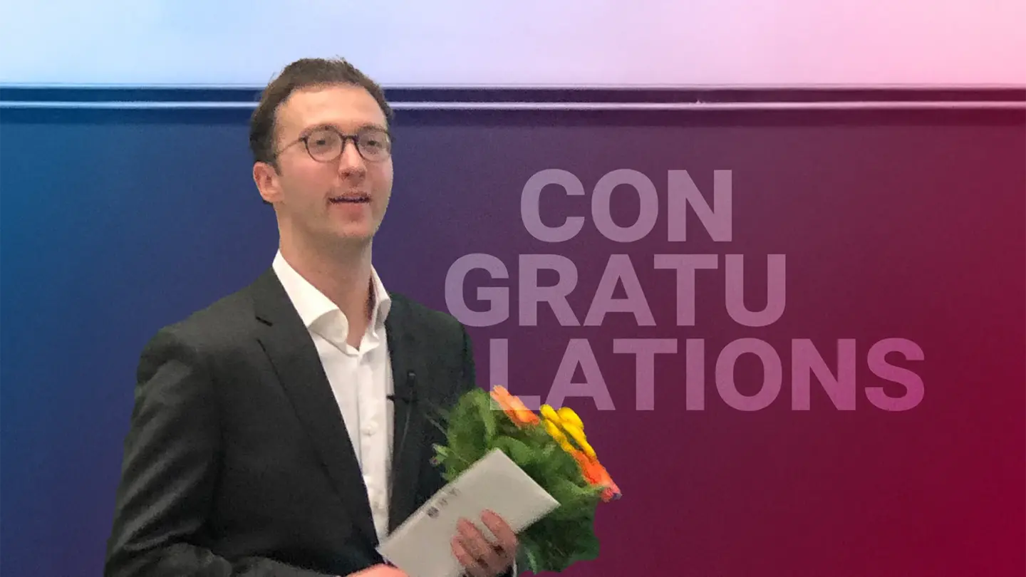 Giulio Zucal after he finished his dissertation, standing in front of a blackboard with a bunch of flowers and a document in his hands