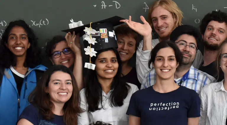 Nidhi Kaihnsa in the middle of a group of scientists. She is wearing a doctoral hat.