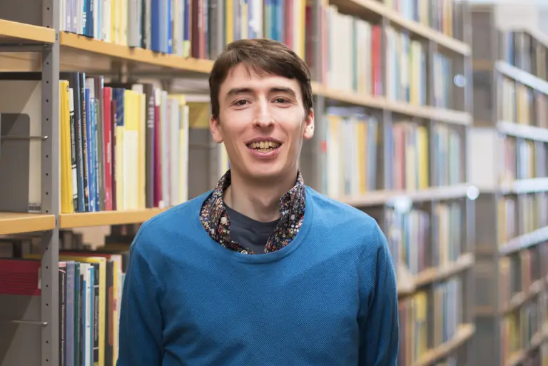 Porträt von Sam G. Krupa vor Bücherregalen