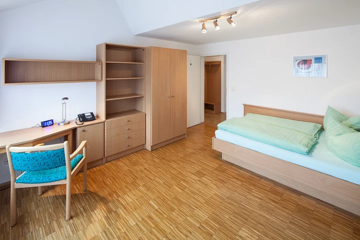 A bedroom with bed, desk and empty cabinets