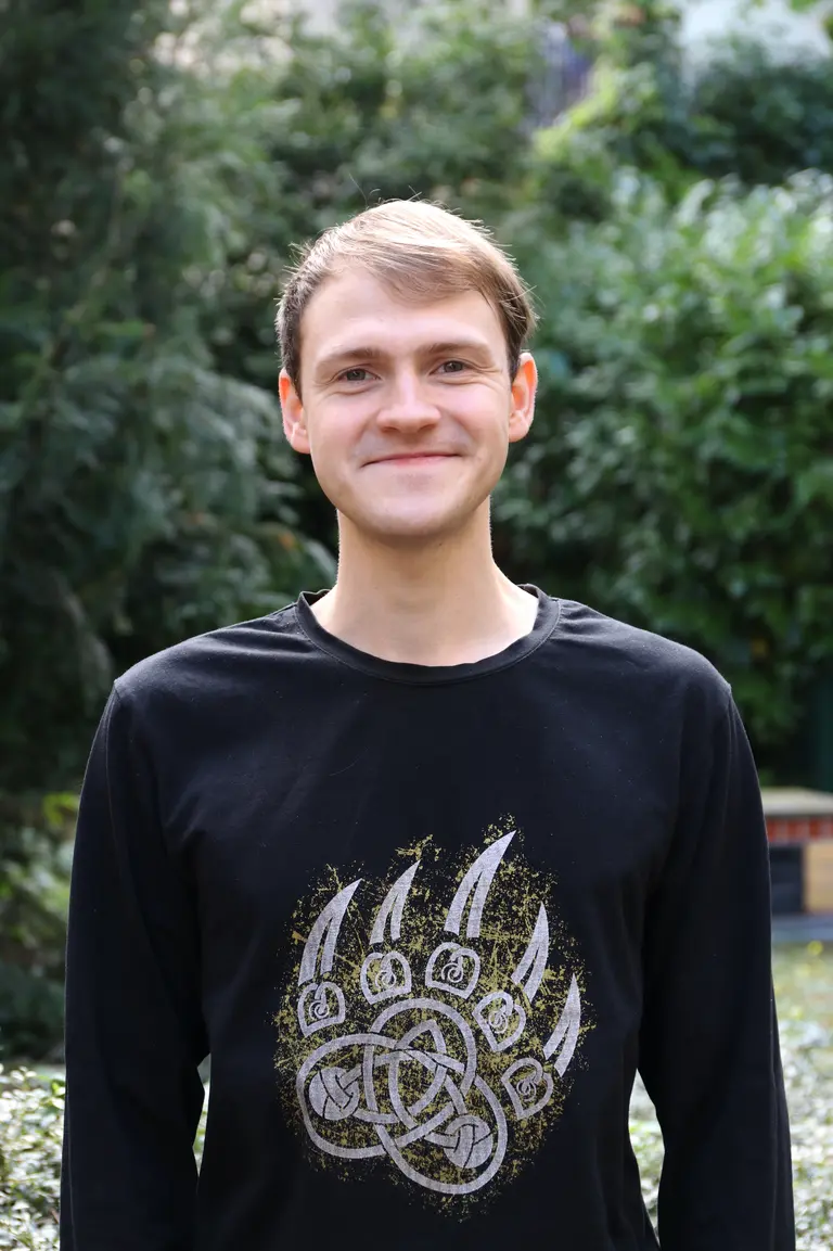 Portrait of Mikhail Glazkov outside in front of green plants