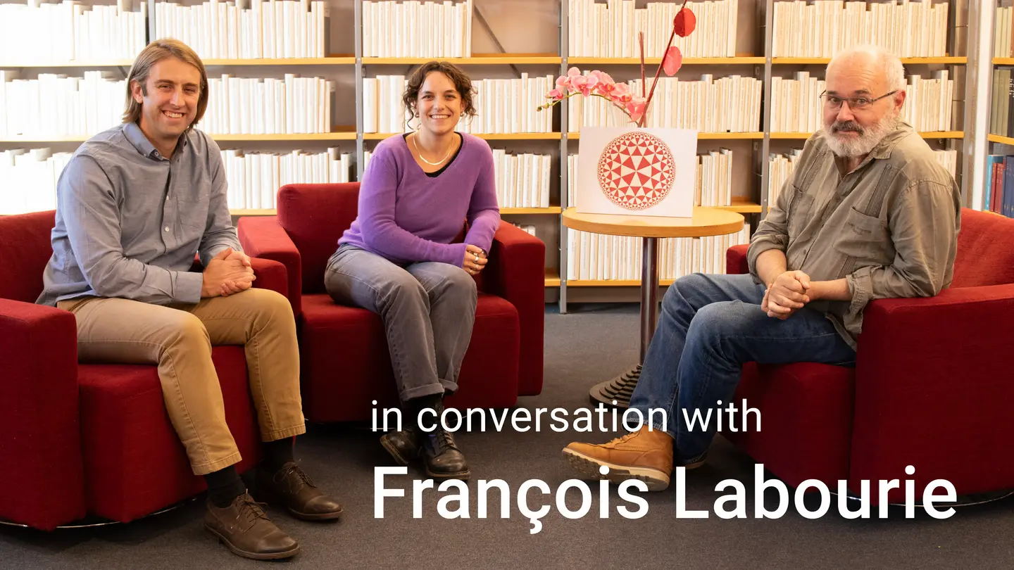 “In Conversation with François Labourie”: Jeff Danciger, Xenia Flamm and François Labourie sitting and smiling in red armchairs in the library