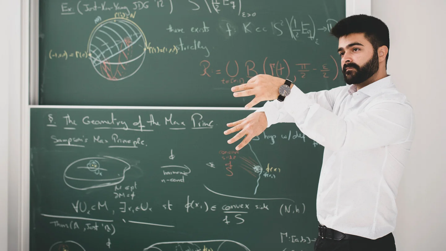 Renan Assimos Martins is giving a lecture in front of a blackboard
