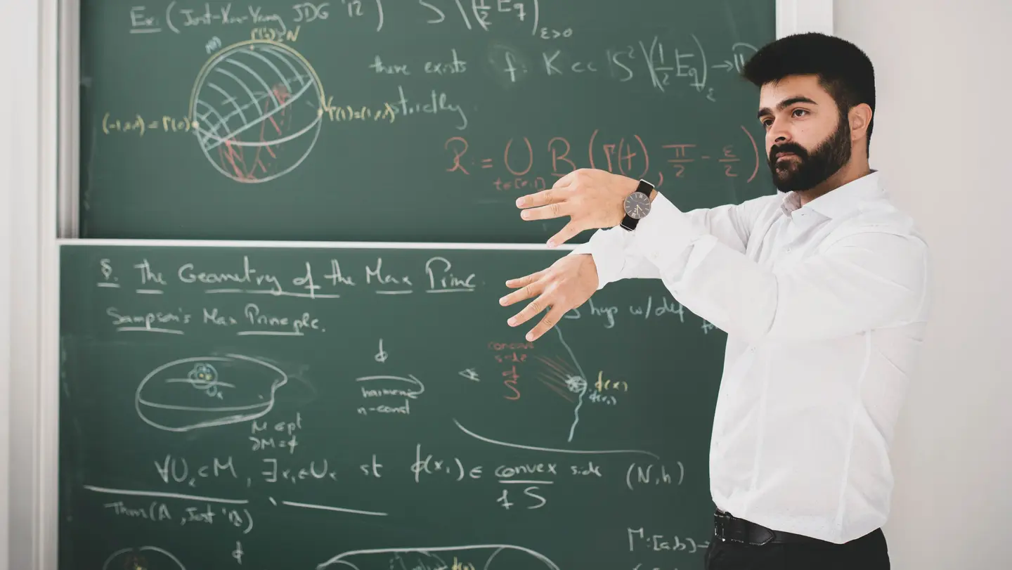 Renan Assimos Martins is giving a lecture in front of a blackboard