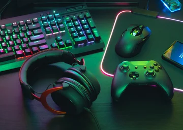 Auf einem Tisch liegende Gegenstände: Kopfhörer, Gaming-Tastatur und -Maus