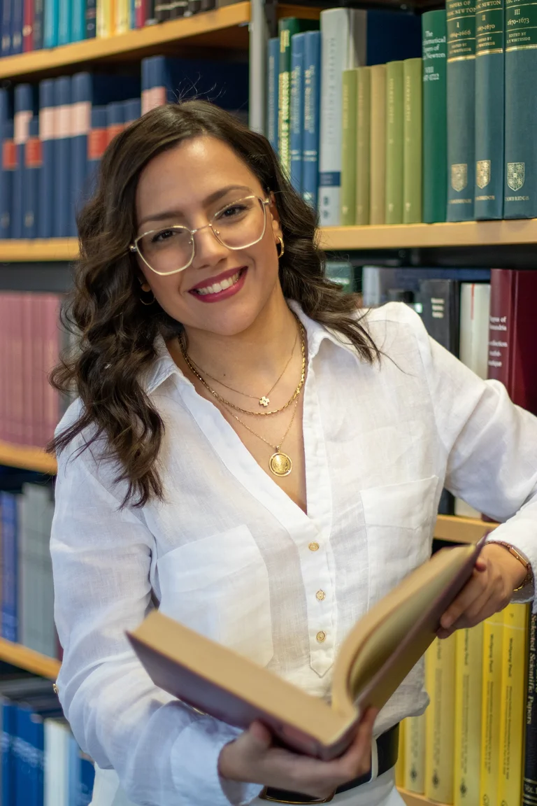 Portrait of Georgiana Chatzigeorgiou in front of a row of books in the library