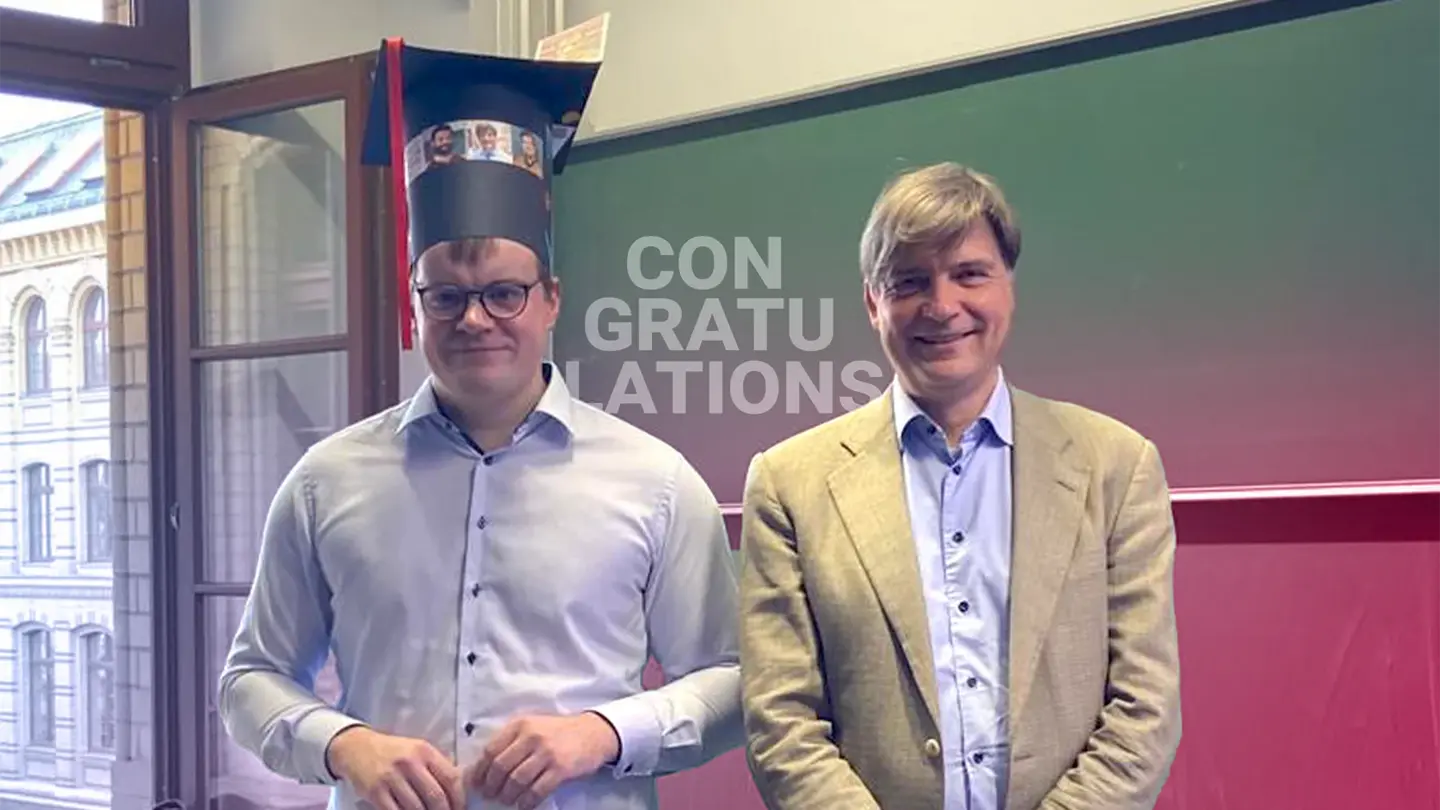 Christian Wagner and Felix Otto are standing in front of a blackboard and smiling; the text “Congratulations” in the background is visible