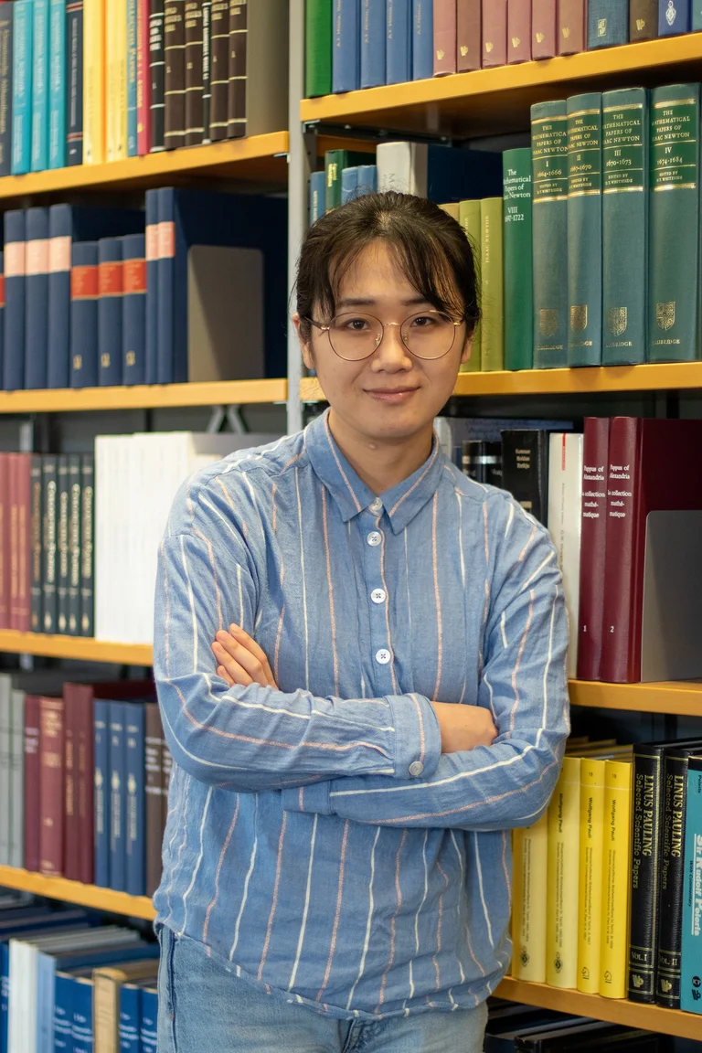 Portrait of Jing An in front of a row of books in the library